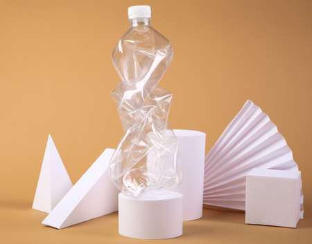 Plastic bottle and geometric shapes on beige background. Environmental pollution, ecology, concept...