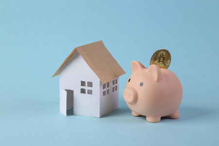 Piggy bank with bitcoin and model house on blue background. Saving conceptの写真素材