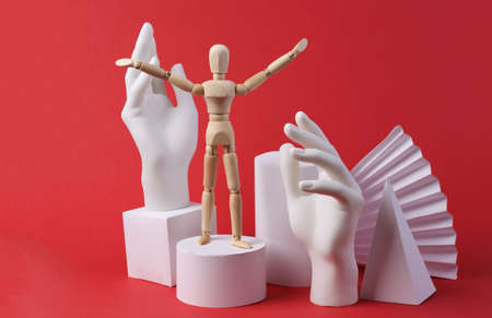 Abstract composition of different geometric shapes, hands, wooden puppet on a red background. Concept art, minimalismの写真素材