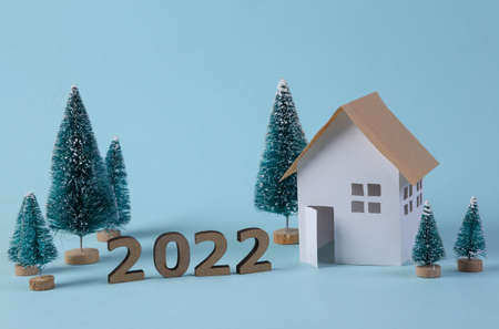 new year composition. House model and a Christmas tree on blue background. new year 2022
