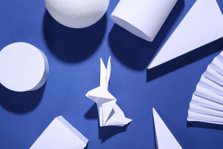 Minimalism blue easter background with geometric shapes and origami rabbit. trendy shadows