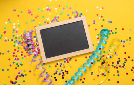Chalk board and confetti with streamer on yellow backgroundの写真素材
