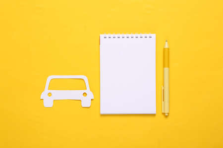 paper cut car and notebook on yellow backgroundの写真素材