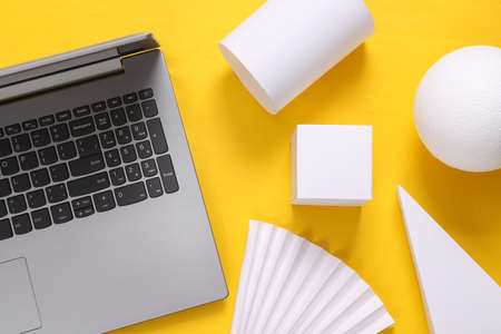 Laptop and geometric shapes on a yellow background. top view