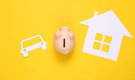 Paper-cut house and car, piggy bank on yellow background. save money. propertyの写真素材