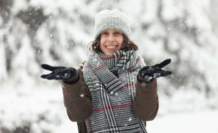 Cheerful woman in warm clothes enjoying the falling snowの写真素材