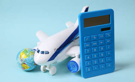 travel concept. Toy passenger plane, calculator and globe on a blue pastel background.の写真素材