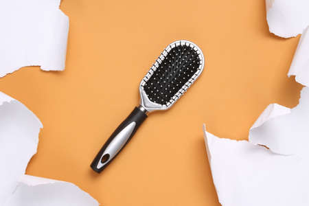 Hair brush and white torn paper sheets on beige background. minimalist background. top view. copy spaceの写真素材
