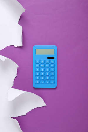 Calculator and white torn paper sheet on purple background. business concept. top viewの写真素材