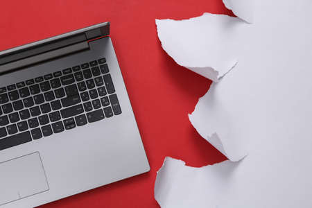Laptop and torn paper sheet on red background. top view.の写真素材