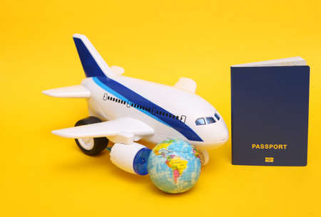 travel concept. Toy passenger plane, globe and paqssport on yellow background.