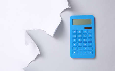 Calculator and torn paper sheet on gray background. business concept. copy spaceの写真素材