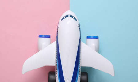 Model of toy passenger plane on blue-pink pastel background. travel concept. top view