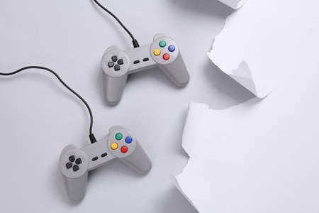Retro gamepads and torn paper sheet on gray background. gaming concept. top view. copy spaceの写真素材