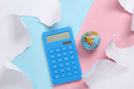 Calculator and globe on blue-pink background with torn paper. concept art. Pastel color trend....