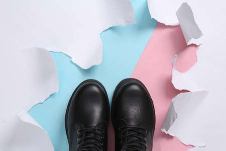 Pastel color trend. Black leather shoes on a blue-pink background with torn paper. concept art....
