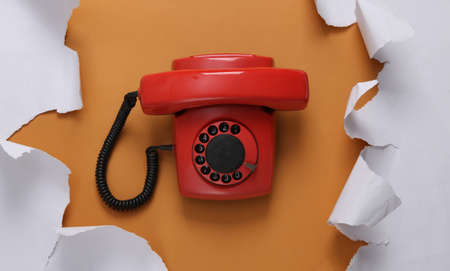 Retro rotary phone and torn paper sheets on beige background. top view