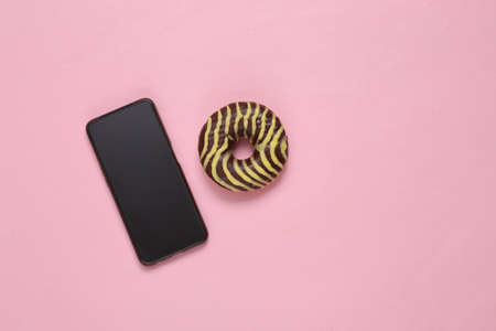 Smartphone and donut on pink backgroundの写真素材