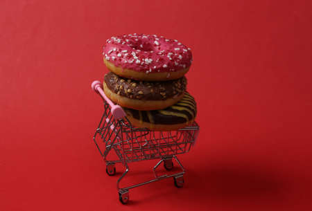 Mini shopping cart with a stack of donuts on a red background
