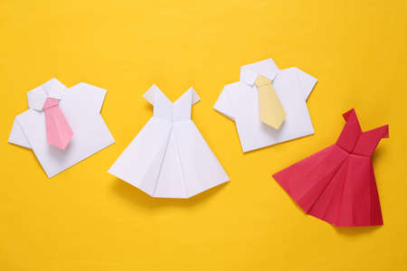 Origami dresses and shirts with tie on yellow background