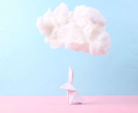 Origami bunny with fluffy cloud on pastel pink blue background. creative easter idea. minimal concept. pastel color trendsの写真素材