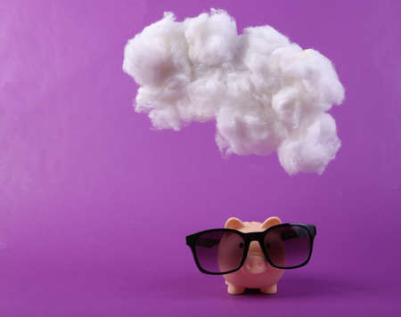 Piggy bank with sunglasses with cloud on purple background. creative ideas. Summer rest. minimal concept.の写真素材