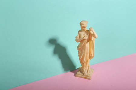 Antique statue on blue-pink pastel background. minimalism. trendy shadow. creative layout.の写真素材