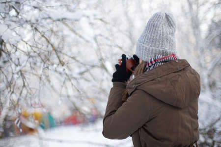 Woman photographer with retro camera in snowy weather at winterの写真素材