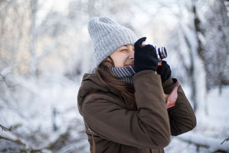 Woman photographer with retro camera in snowy weather at winter