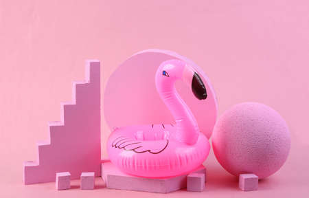 Scene with geometric shapes and infatable flamingos. pink background. Pastel color trend....