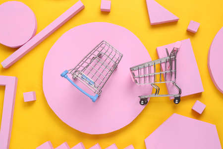 Shopping trolley on yellow background with pink geometric shapes. flat layの写真素材