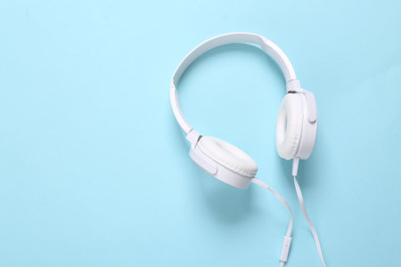 White stylish stereo headphones on a blue background. Minimalistic music still life, music lover....