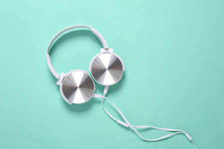 White stylish stereo headphones on mint green background. Minimalistic music still life, music lover. top view. flat layの写真素材
