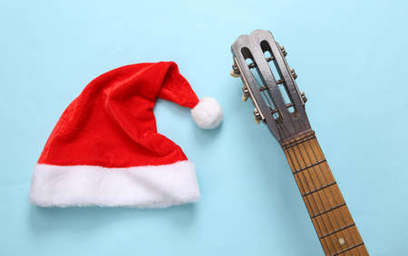 Acoustic guitar with santa hat on a blue background. Musical, christmas concept. top viewの写真素材