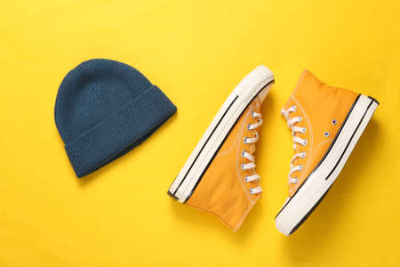 Beanie and sneakers on yellow background. youth concept. top viewの写真素材