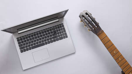 Acoustic guitar neck and laptop on gray background. Online guitar lessons. musical concept. top view. flat layの写真素材