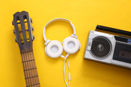 Flat lay music still life. Acoustic guitar neck, audio cassette player and headphones on yellow background. musical concept. top view.の写真素材