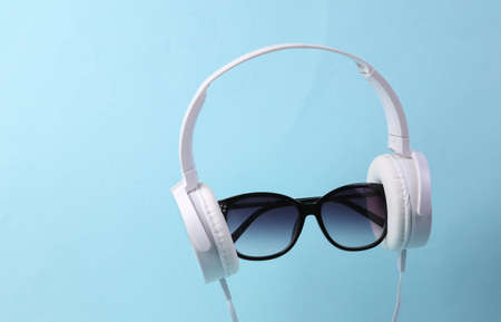 White stereo headphones with sunglasses on blue backgroundの写真素材