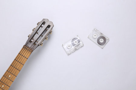 Acoustic guitar neck and audio cassette on a gray background. musical concept. minimalism. top view....