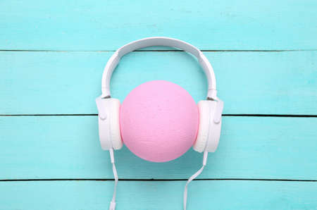 Headphones worn on pink ball on blue wooden background. creative layout. Minimalism music conceptの写真素材