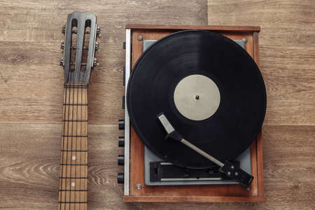 Acoustic guitar and retro vinyl record player on wooden floor. musical concept. top view. flat lay