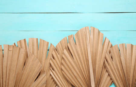Tropical minimalist background. Dry palm leaves on a blue wooden background. top view