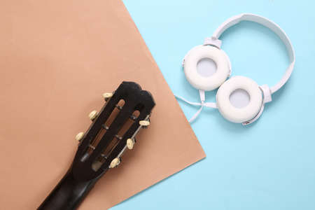 Acoustic guitar neck and headphones on brown blue background. Online guitar lessons. musical concept. top view. flat layの写真素材