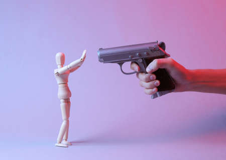 The hand with the pistol is aimed at the puppet with raised arms. Crime, extortionの写真素材