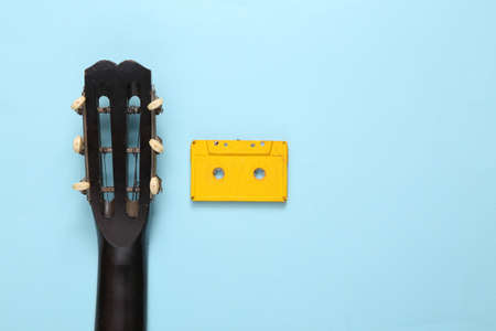 Acoustic guitar, audio cassette on blue background. musical concept. minimalism. top view. flat lay....