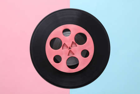 Pink retro audio reel and vinyl record on blue pink background. Minimalism music concept. top view