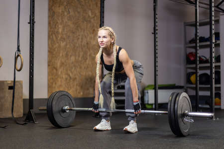 Muscular Woman performs deadlift with weight in modern functional gymの写真素材