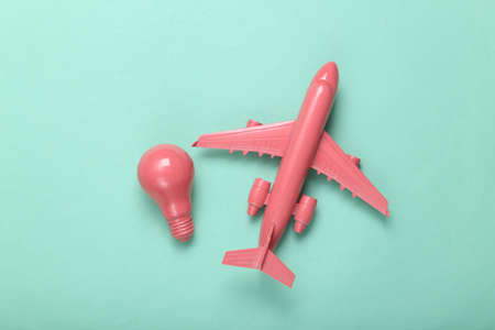 Minimal travel layout. Pink plane and light bulb on mint blue background. fresh ideas. flat lay. top viewの写真素材