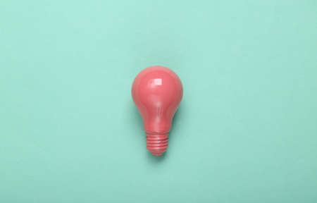 Pink light bulb on mint green background. minimalism. creative layout. fresh ideas. top view. flat...