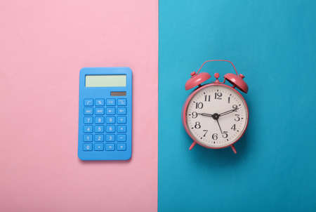 Pink alarm clock and calculator on mint green background. minimalism. top view. flat layの写真素材